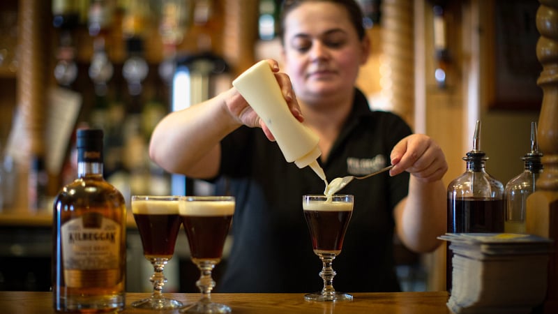 Bartender pouring glasses of Kilbeggan whiskey