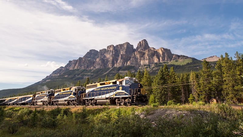 This is the Rocky Mountaineer luxury tourist train winding past Castle Mountain in Banff National Park, Alberta, Canada.