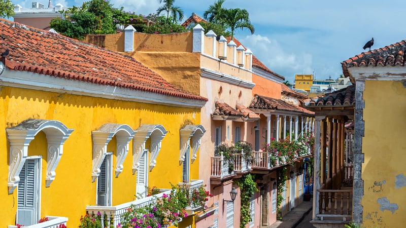 This image shows the vibrant, historic streets of the Walled City of Cartagena (also known as Las Murallas or Centro Histórico) in Cartagena de Indias, Colombia.