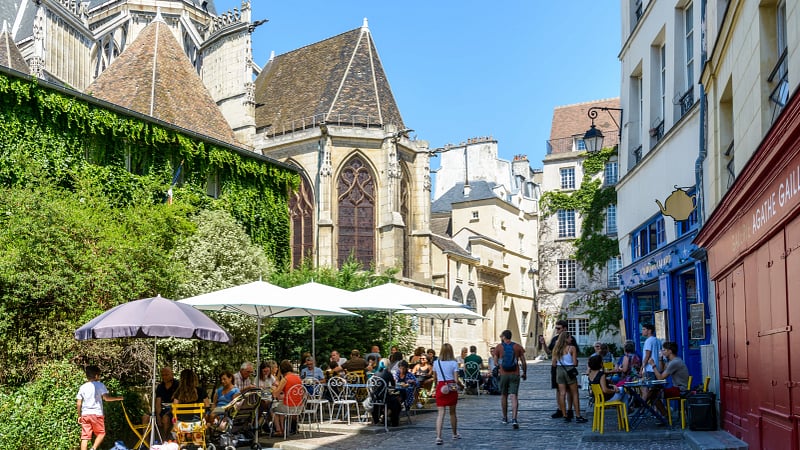 the Church of Saint-Gervais-Saint-Protais towering over a lively pedestrian street scene in the historic Marais district of Paris.