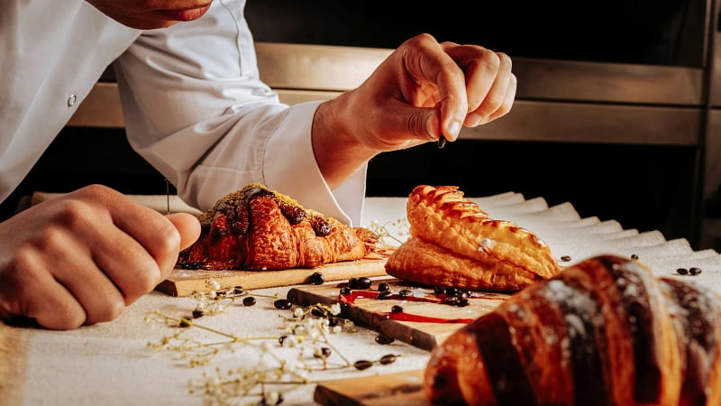 a pastry chef meticulously plating and decorating freshly baked French pastries.