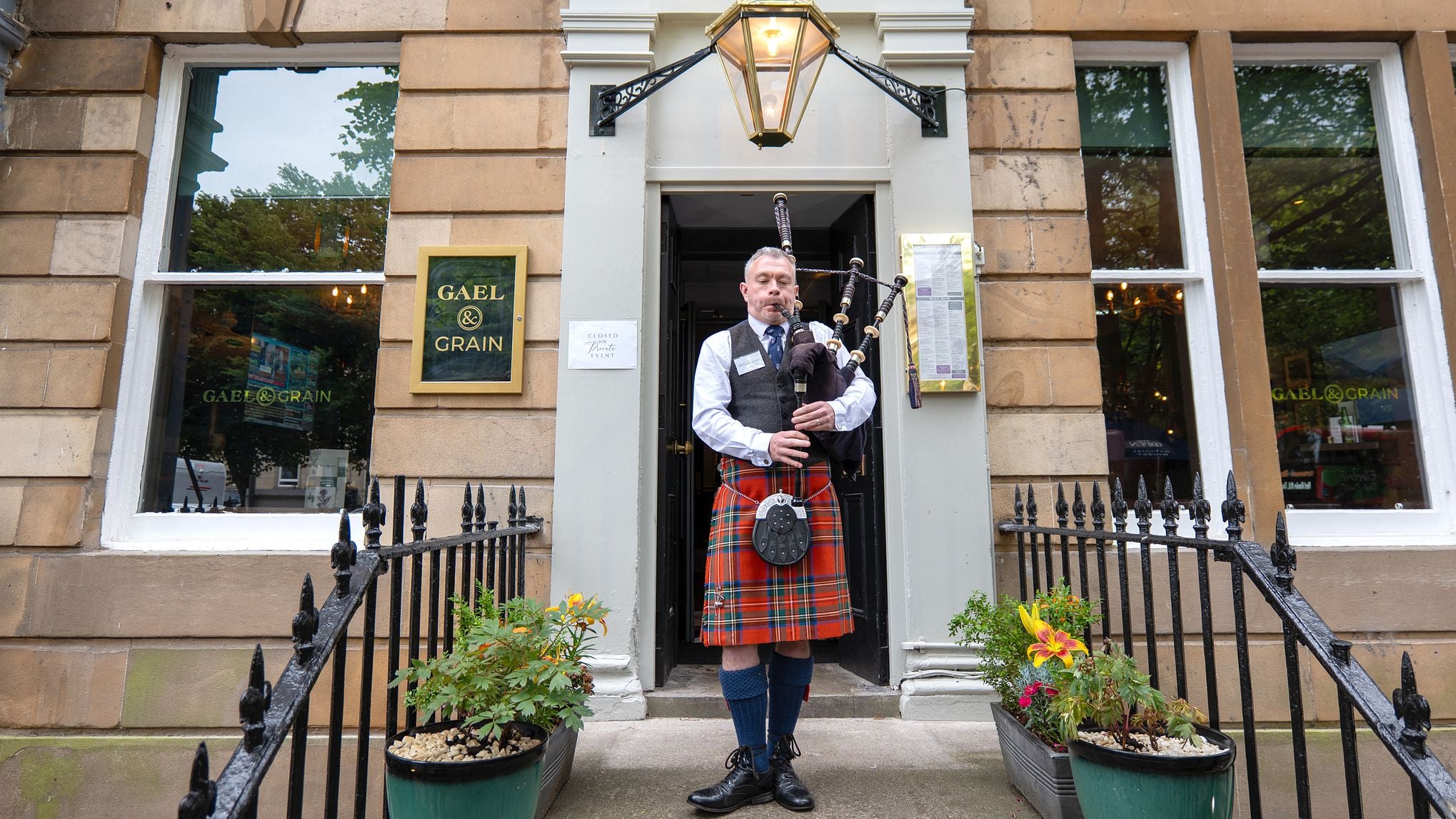 a bagpiper standing outside Gael & Grain, a popular Scottish pub and kitchen located in Glasgow, United Kingdom