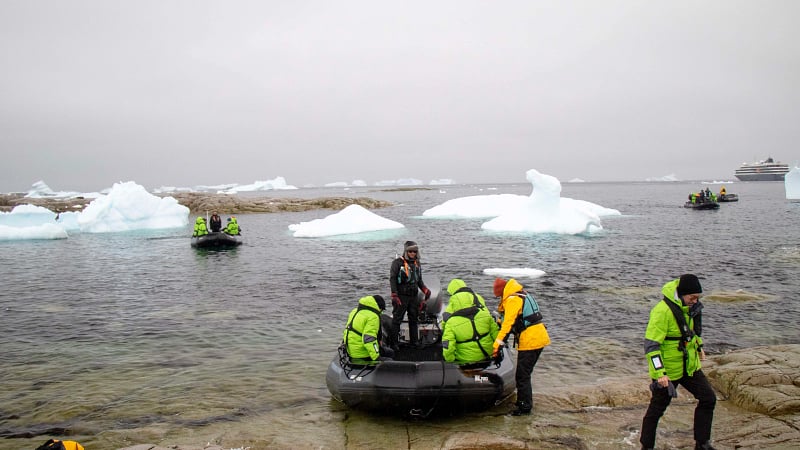 Antarctic expedition where tourists are arriving at a rocky shoreline by rigid inflatable boats (often called Zodiacs).