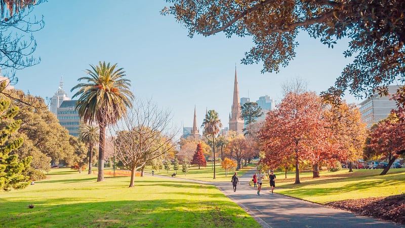 Fitzroy Gardens in Melbourne, Australia, featuring autumn foliage and the spires of St Patrick's Cathedral in the background.