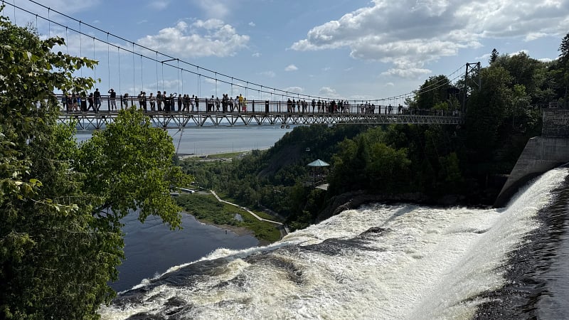 The Montmorency Falls Suspension Bridge spanning directly across the crest of the majestic Montmorency Falls in Quebec, Canada.