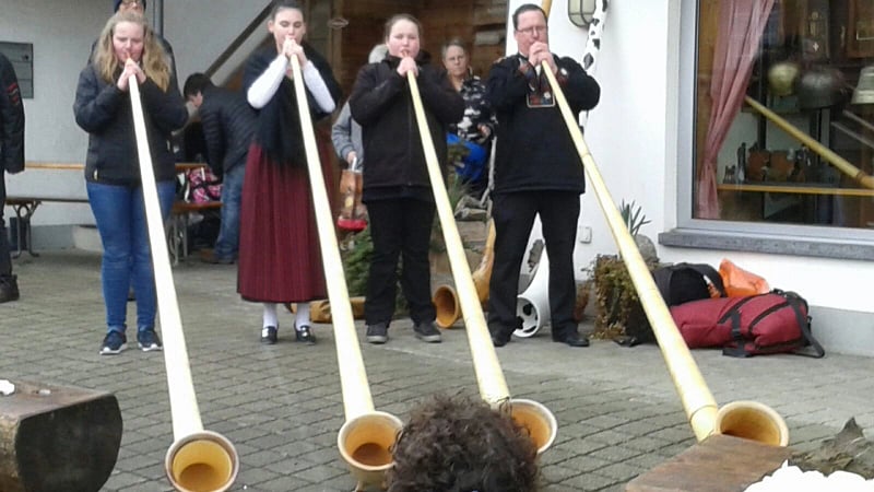 People playing the alphorn (or alpenhorn), a traditional labrophone wind instrument deeply rooted in the alpine culture of Switzerland, Germany, and Austria.