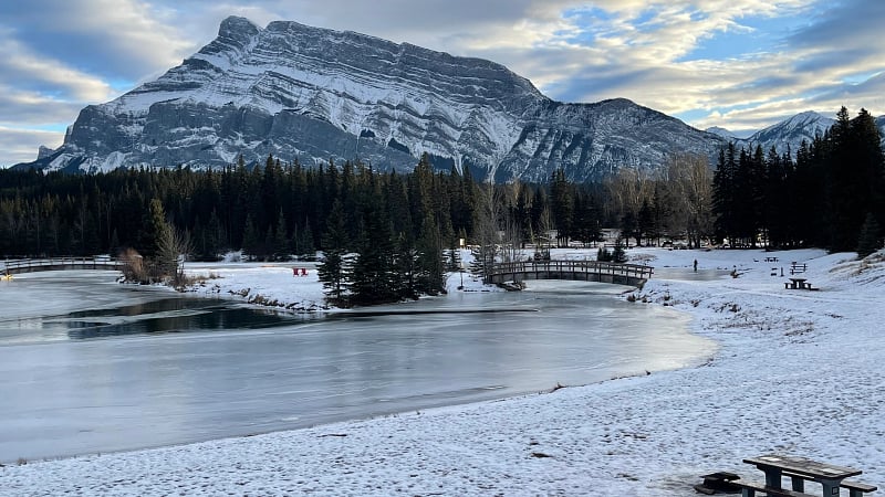 the partially frozen waters of Cascade Ponds, a popular day-use area located just outside the town of Banff within Banff National Park in Alberta, Canada.
