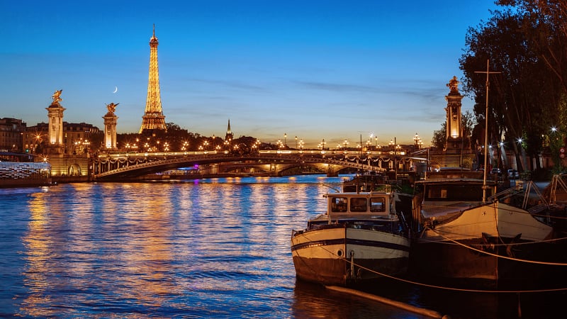 scenic view of the Seine River in Paris, featuring the iconic Eiffel Tower illuminated at night.