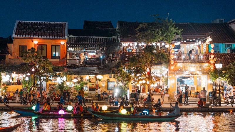 Hoi An, Vietnam at dusk with boats cruising on river side with lantern