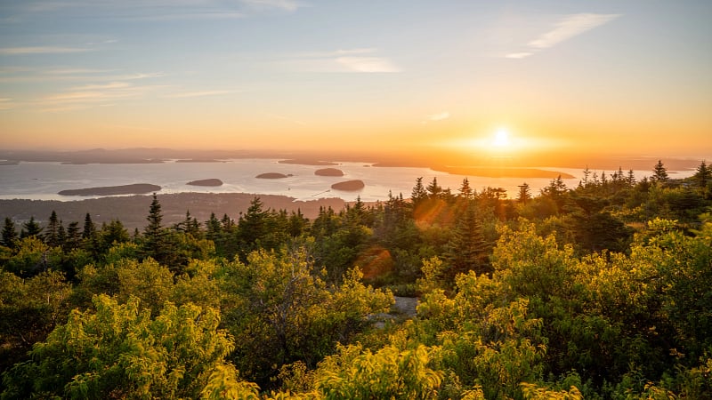 This image displays a breathtaking sunrise viewed from the summit of Cadillac Mountain, which is located in Acadia National Park near Bar Harbor, Maine.