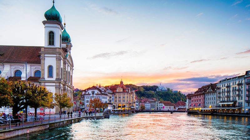 This image captures a vibrant sunset over the Reuss River in the historic city of Lucerne, Switzerland.