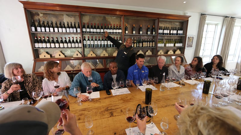 Group of people participating in a guided wine tasting session at the historic Spier Wine Farm, located in the Stellenbosch region of South Africa.