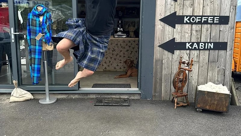 a man mid-leap in front of the Prickly Thistle textile mill and studio, an eco-conscious artisan weaving workshop located in the Scottish