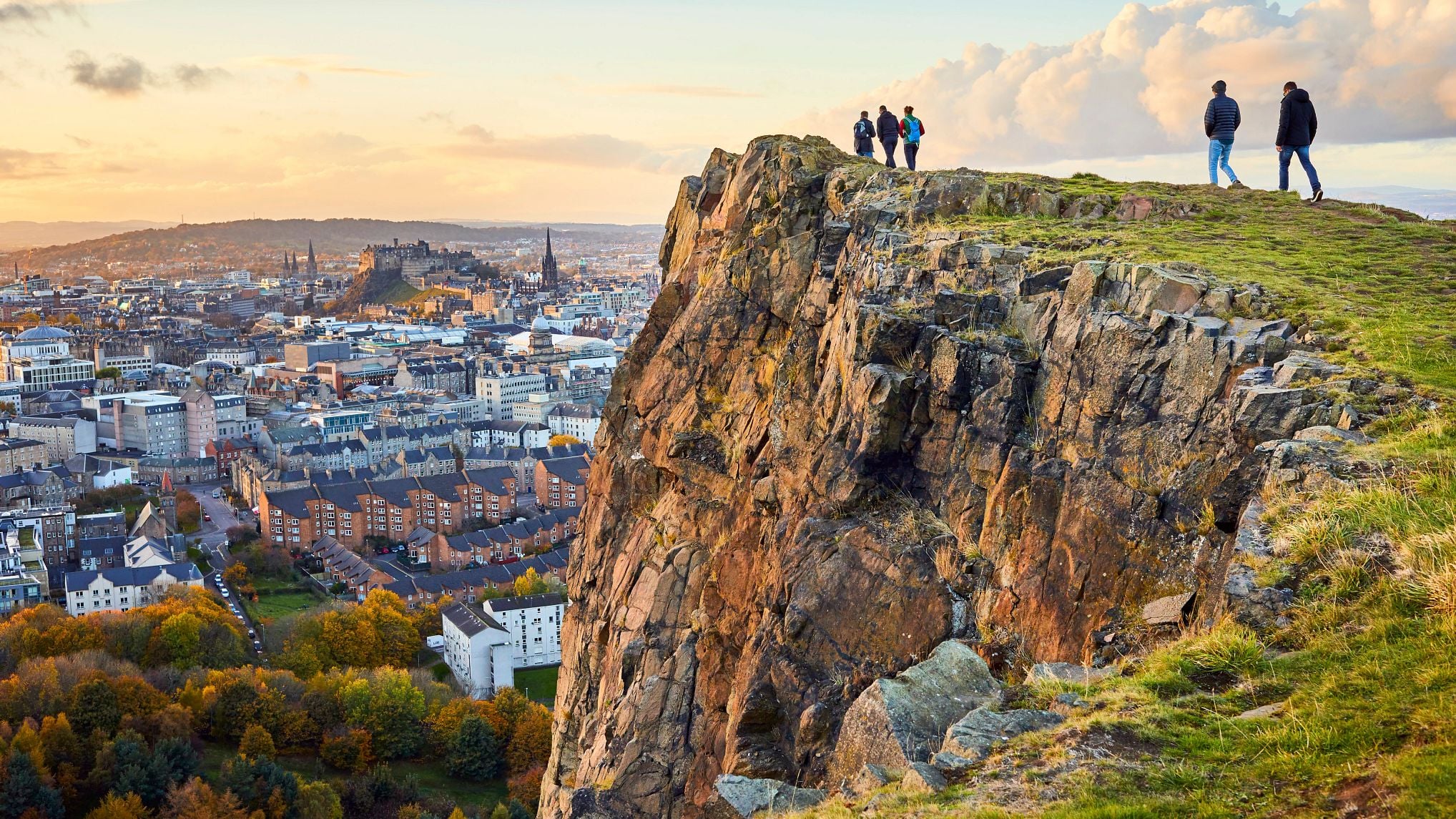 Group of people walking along cliff edge looking at city views