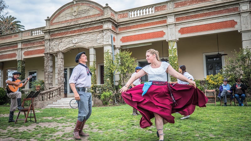 a folkloric dance performance taking place in front of a historic estancia in Argentina.