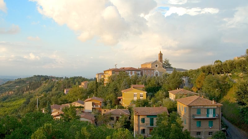 Storm clouds loom over the picturesque hilltop town of Montepulciano in Tuscany, Italy, highlighting its historic buildings and rolling countryside.