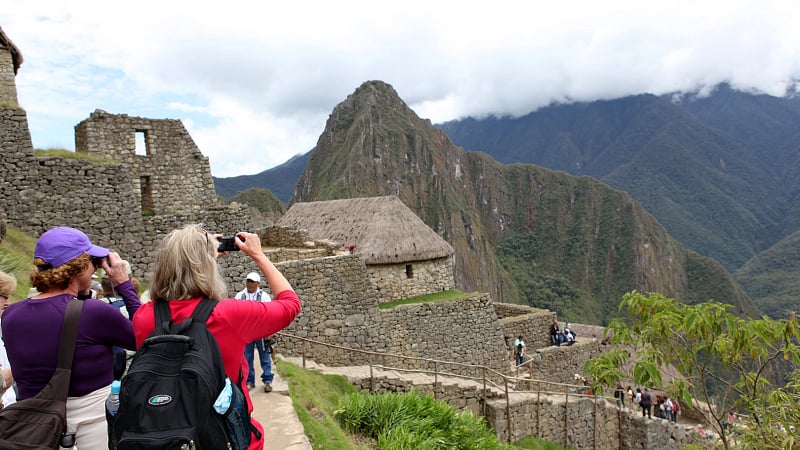 the famous 15th-century Inca citadel of Machu Picchu in Peru, looking toward the iconic sharp peak of Huayna Picchu rising in the center background.